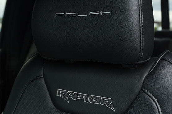 Black leather car seat featuring "Roush" embroidered on the headrest and "ROUSH Raptor" stitched on the backrest, designed for off-road racing enthusiasts seeking high-performance suspension.