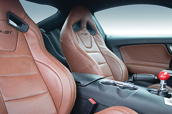 This muscle car's interior features two brown leather bucket seats, a central console, and a striking red gear shift knob, perfectly complementing the power of its 727-horsepower engine.