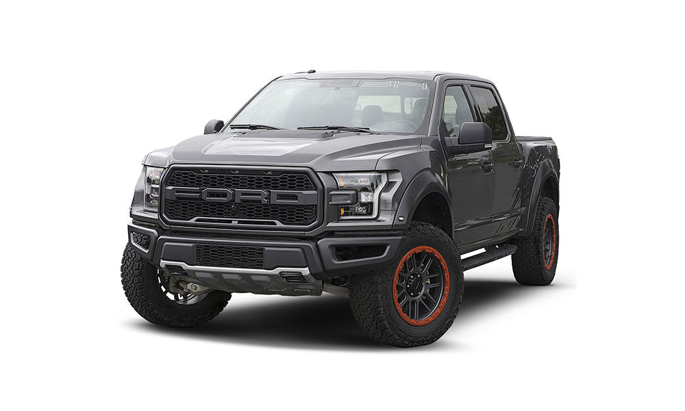 Gray pickup truck with large tires, front grille, and orange accents, showcased on a white background. Featuring ROUSH Raptor styling and high-performance suspension for off-road racing adventures.