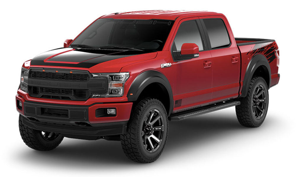 The ROUSH F-150 in red and black boasts all-terrain tires, a sleek black grille, and side graphics. Its Fox 2.0 suspension system adds to its commanding presence as it sits parked on a white background.