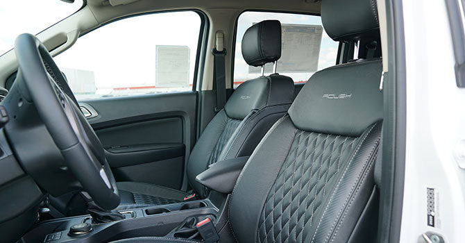 Interior view of the ROUSH Ranger's front seats, featuring black leather with textured stitching, highlighting its off-road prowess.
