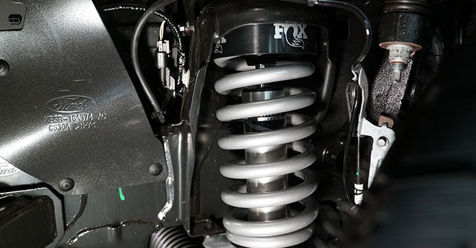 Close-up of a ROUSH Ranger’s suspension system highlighting off-road prowess with a Fox shock absorber and coil spring assembly.