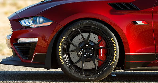 Close-up of a ROUSH Mustang's front wheel, showcasing a black rim, Continental tire, and Brembo brake caliper. This Jack Roush Edition boasts a 775HP supercharger, making it as powerful as it looks.