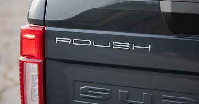 Close-up of a 2021 ROUSH Super Duty's rear, featuring the "ROUSH" badge near the tail light on a grey exterior. This powerhouse rides on General Grabber A/TX tires, offering unmatched grip and durability.