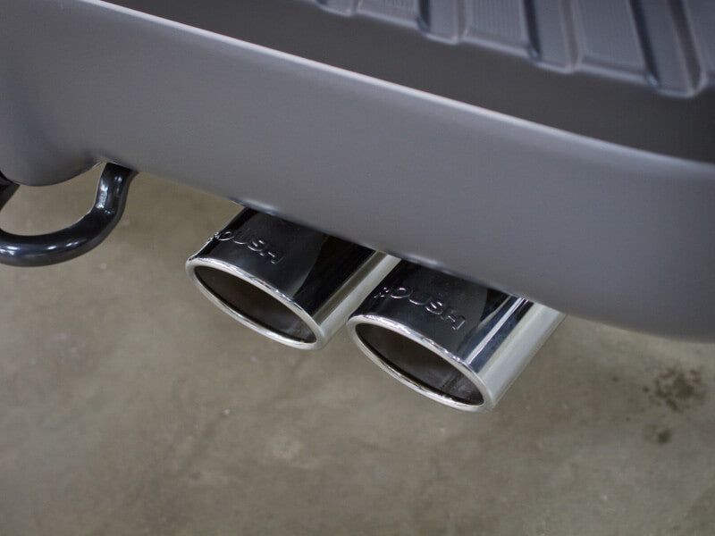 Close-up of dual chrome exhaust pipes on a vehicle, positioned horizontally beneath a gray bumper, hinting at the power of the 6.2L V8 engine roaring within.