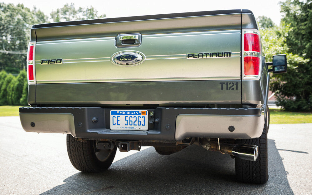 Rear view of a green Ford F-150 Platinum truck with Michigan license plate CE 56263, parked on a sunny day, showcasing its sleek Roush exhaust.