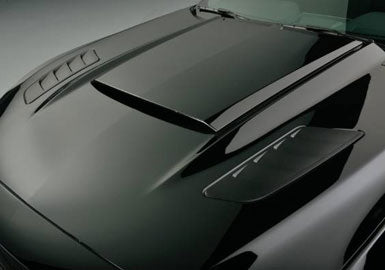 Close-up view of a glossy black 2015 Mustang GT hood featuring a prominent central scoop and two vented Mustang Heat Extractors on the side panels.