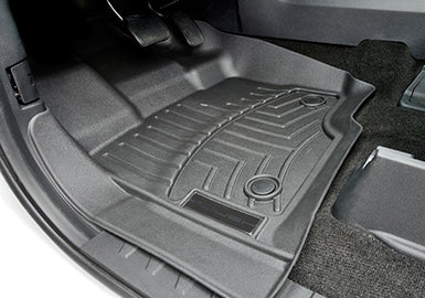 The Roush WeatherTech Floor Mat features grooves and raised edges, perfectly molded to fit the F-150 driver's side footwell, ensuring optimal interior protection. Visible pedals rest just above, enhancing your vehicle's style and safeguarding against daily wear.