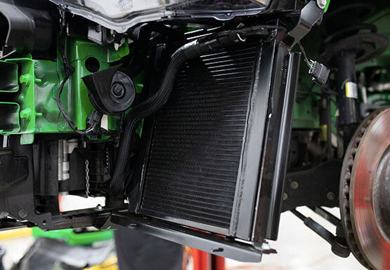 Close-up view of a Mustang cooling system featuring the ROUSH Stage 3 Max Cooling Upgrade, highlighting the radiator, wiring, and wheel assembly in the engine compartment.