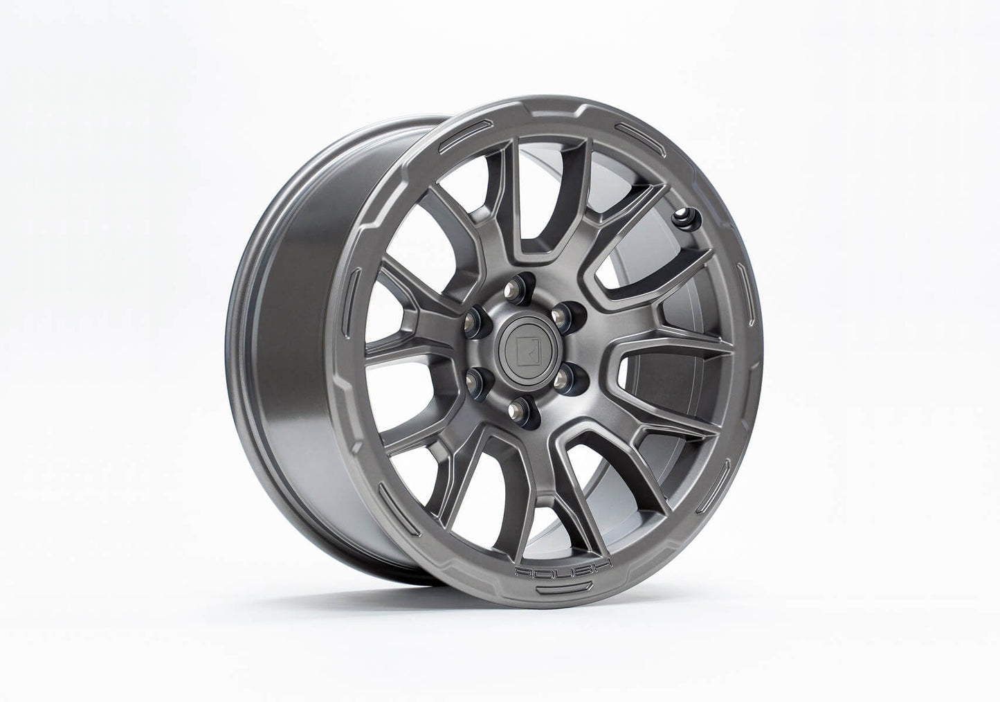 A silver alloy wheel with a multi-spoke design and an Iridium Grey finish shines prominently against a white background, showcasing the sleek sophistication of Roush F-150 wheels.