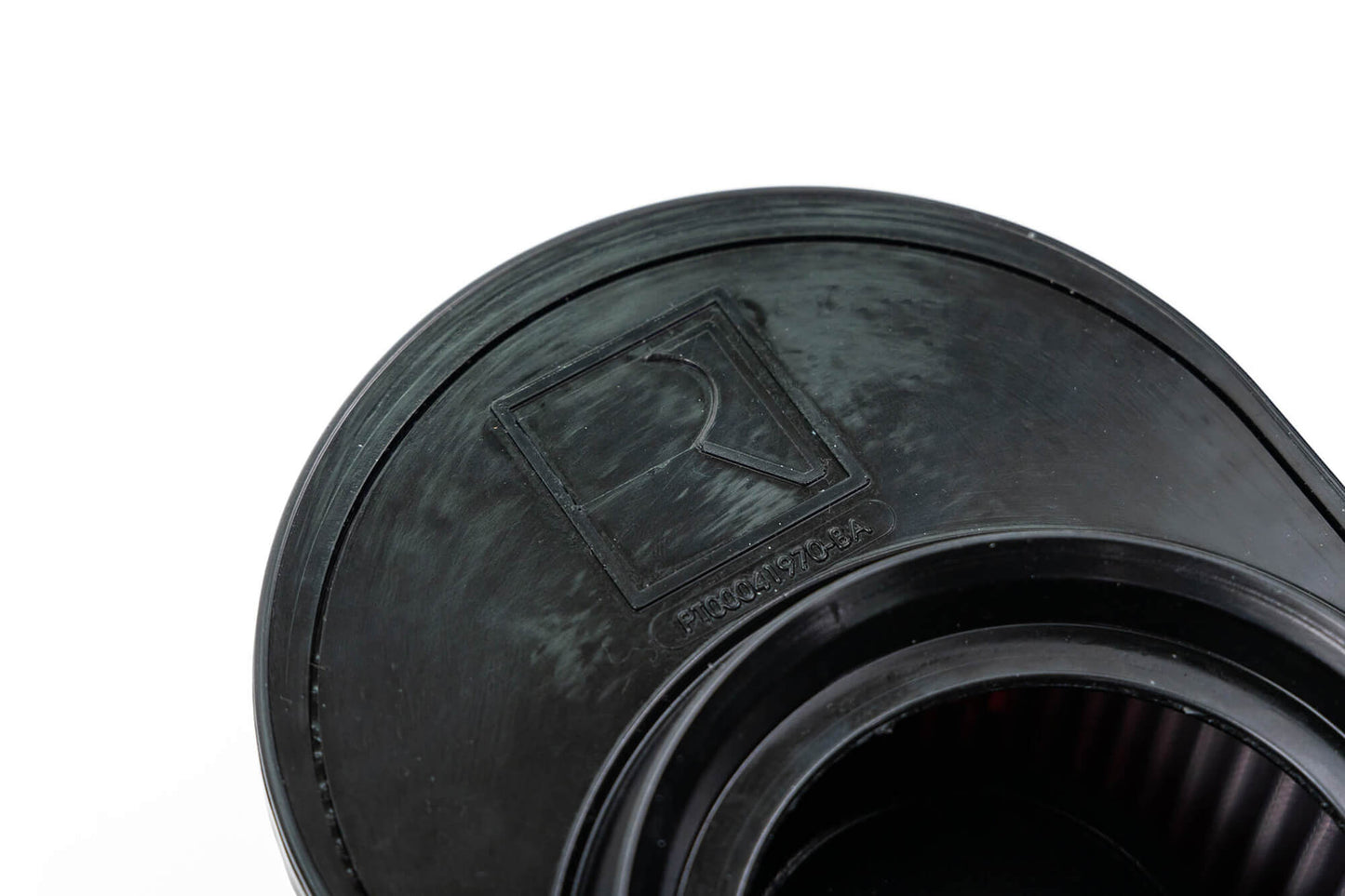Close-up of a black plastic object with a raised rectangular emblem featuring the letter "R" and the text "STOCK 703-3" embossed beneath it, hinting at its connection to a Ford Bronco's off-road racing experience.