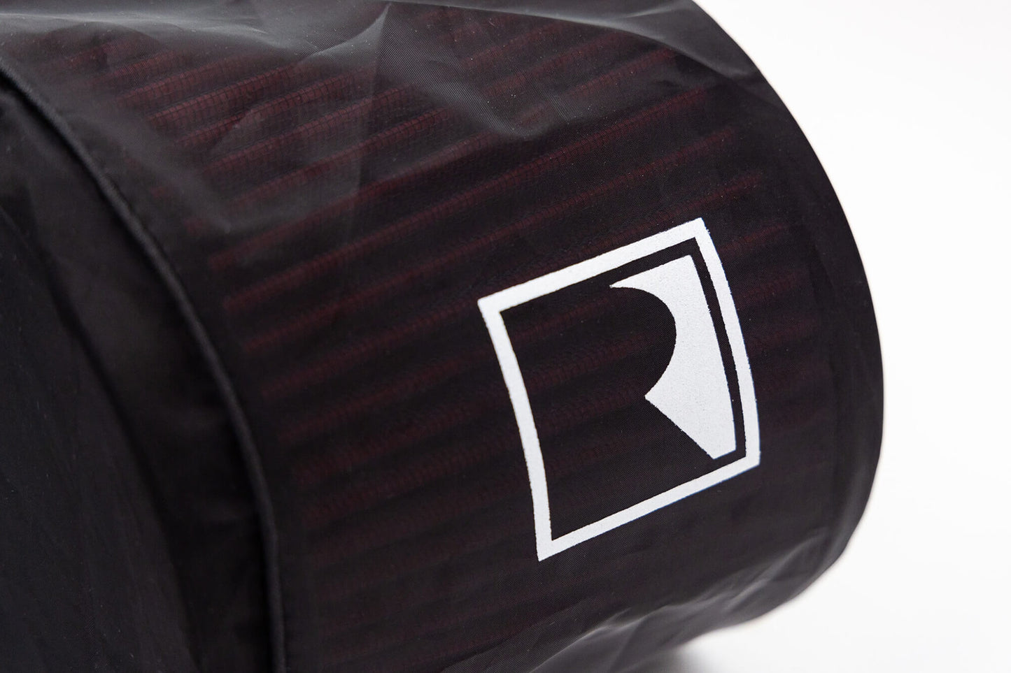 Close-up of a black and red textured cylinder with an "R" logo in a white square, reminiscent of the rugged performance found in the Roush Bronco Air Induction System.
