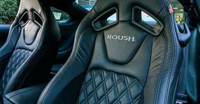 Black leather car seats with "ROUSH" embroidered, featuring diamond stitching and racing-style harness openings, perfect for enhancing your Mustang's performance.