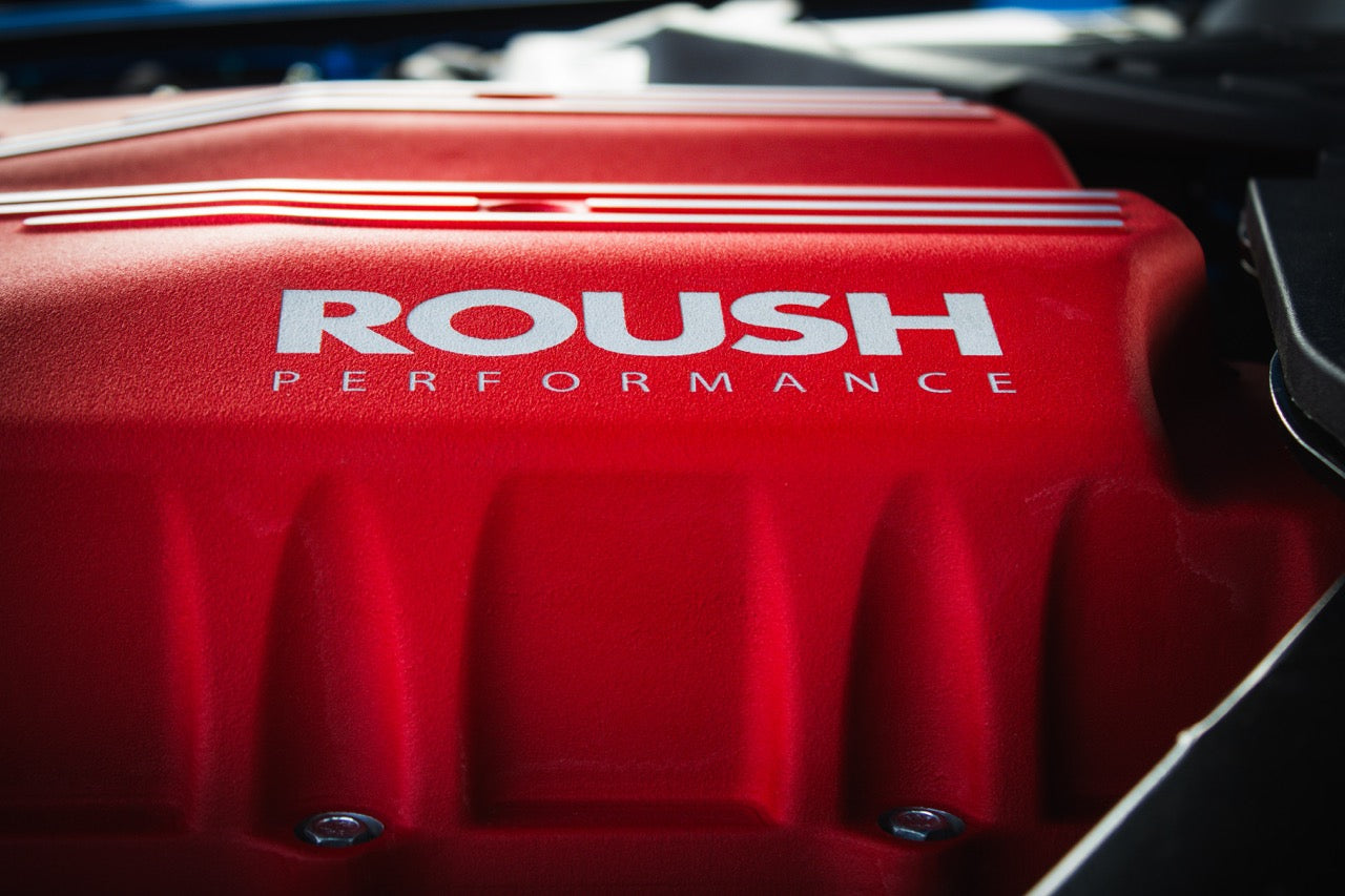 Close-up of a red Roush Performance engine cover with white lettering, hinting at the raw power of a supercharger kit capable of unleashing 740 horsepower.