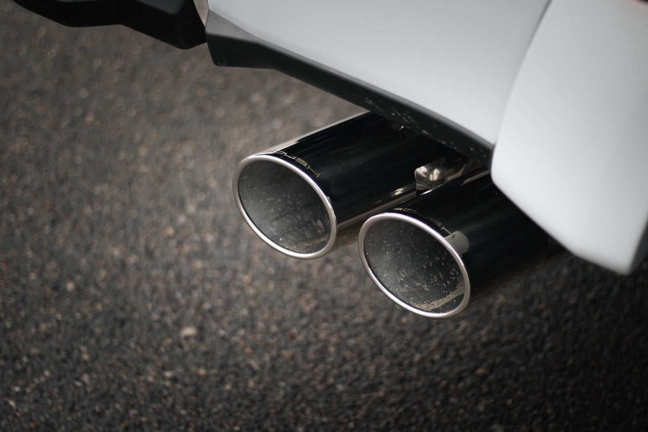 Close-up of dual chrome exhaust pipes on a vehicle, crafted from durable 304 stainless steel, with a textured asphalt surface in the background.