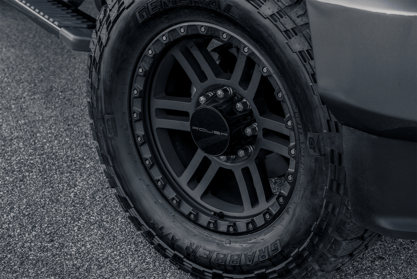 Close-up of a rugged off-road vehicle tire with "General Grabber" branding on an asphalt surface, featuring a heat-extracting hood vent from the 2022 ROUSH F-150.