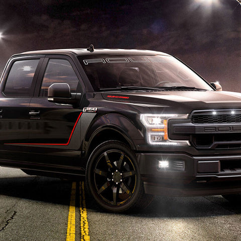 A black ROUSH NITEMARE Ford F-150 performance street truck parked on a street at night under streetlights, featuring the powerful ROUSH Supercharger System.