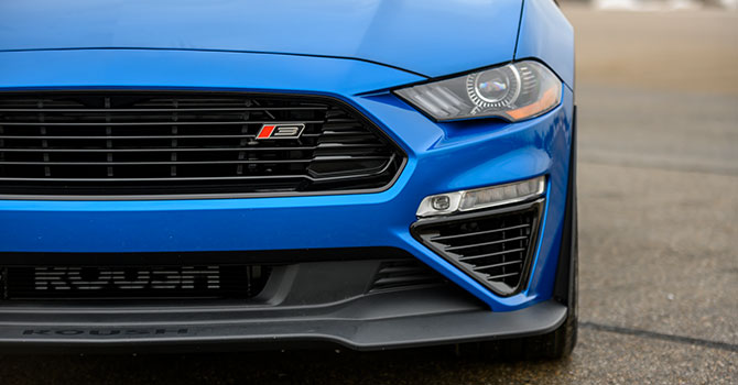 
                  
                    Front view of a blue sports car featuring a distinctive grille and headlight design, complemented by a powerful ROUSH Stage 3 setup on a gray pavement background.
                  
                