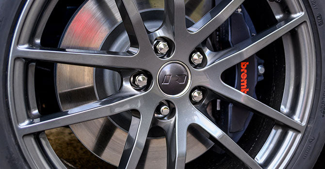
                  
                    Close-up of a car wheel with a metallic alloy rim and visible brake disc, featuring a branded brake caliper, enhanced by the ROUSH Stage 3 package for peak performance.
                  
                
