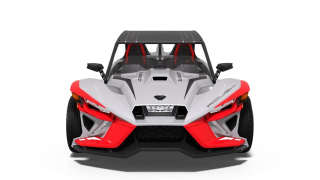 
                  
                    Front view of a three-wheeled, open-air performance vehicle with a white body, red accents, two seats, and a black roof, photographed on a plain white background—a true display of racetrack attitude.
                  
                