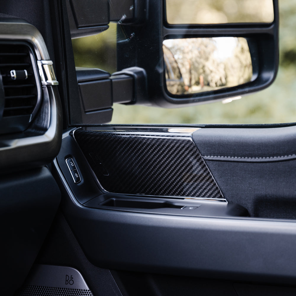 
                  
                    Close-up view of a Roush Super Duty car's interior showing the door panel, side mirror, window controls, and carbon fiber trim.
                  
                