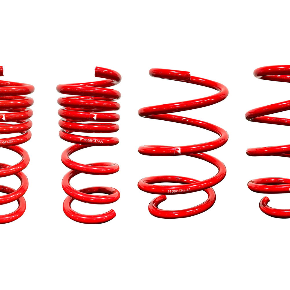 Four red coil springs of varying heights and coils, arranged side by side against a white background, evoke the precision of Roush Mustang Lowering Springs. Their design hints at optimized spring rates and promises an aggressive drop for the discerning car enthusiast.