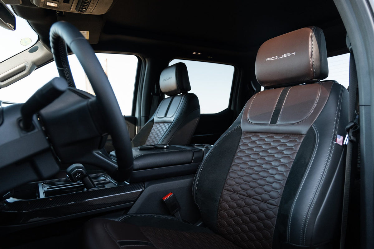 
                  
                    Interior of a 2025 Roush F-150 showing black and brown leather seats with the Roush logo on the headrests.
                  
                