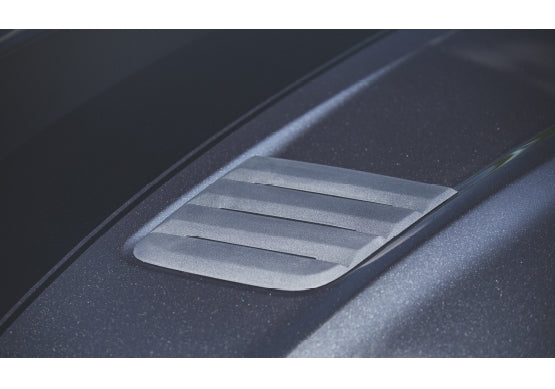 
                  
                    Close-up of a Mustang GT hood with ROUSH Hood Heat Extractors, showcasing three horizontal slats on a metallic dark gray surface.
                  
                