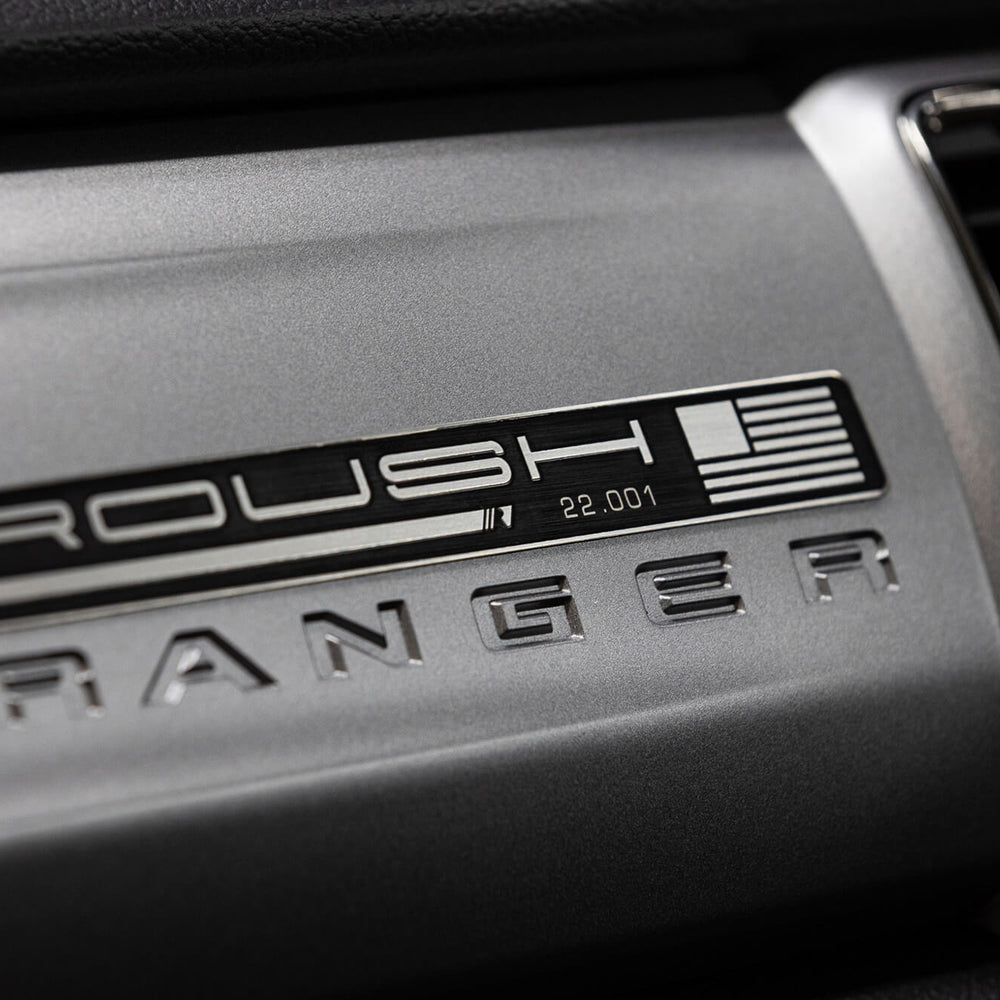 
                  
                    Close-up of a 2022 Roush Ranger's dashboard showcasing the Roush Ranger badge and the serial number 22-001, positioned next to an air vent.
                  
                
