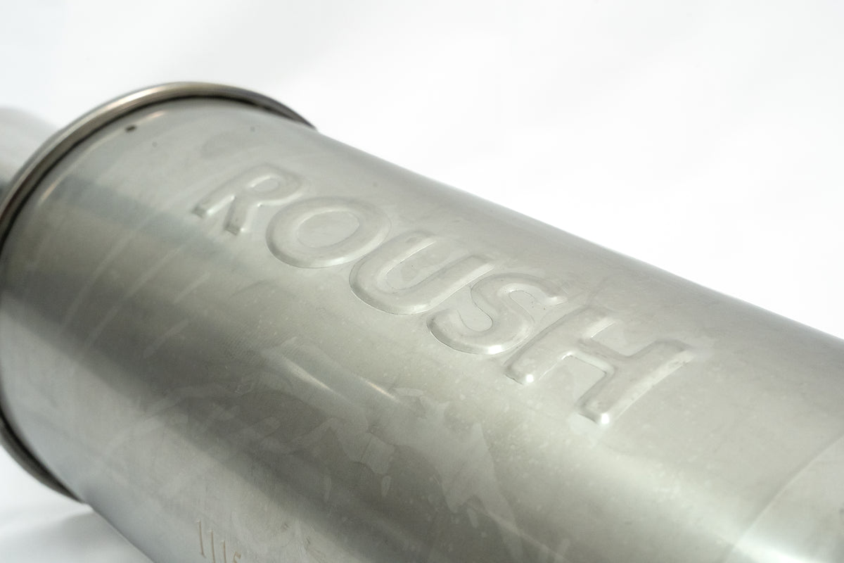 
                  
                    Close-up of a metallic cylindrical object with the word “ROUSH” embossed on its side, likely part of a Roush F-150 cat-back exhaust system, featuring a black tip exhaust and set against a white background.
                  
                