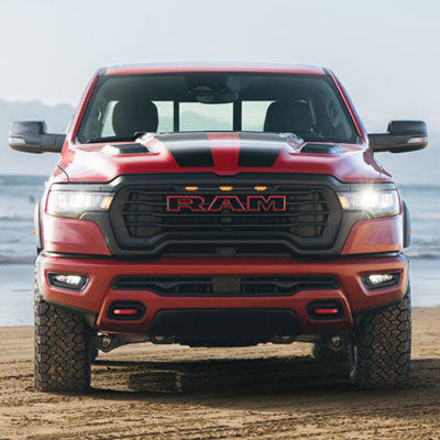 Roush high-flow grille with integrated accent lighting, functional hood heat extractors, paint-matched front bumper, red tow hooks and a red "RAM" grille emblem.