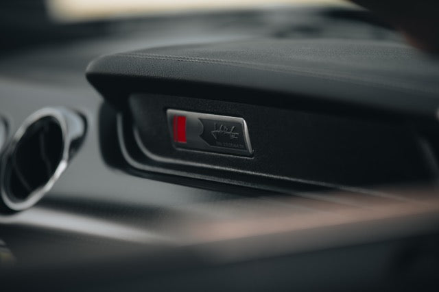 
                  
                    Close-up of a dashboard plaque inside a car, featuring a logo, a red accent, and text indicating this TrakPak Mustang is a limited edition performance track car.
                  
                
