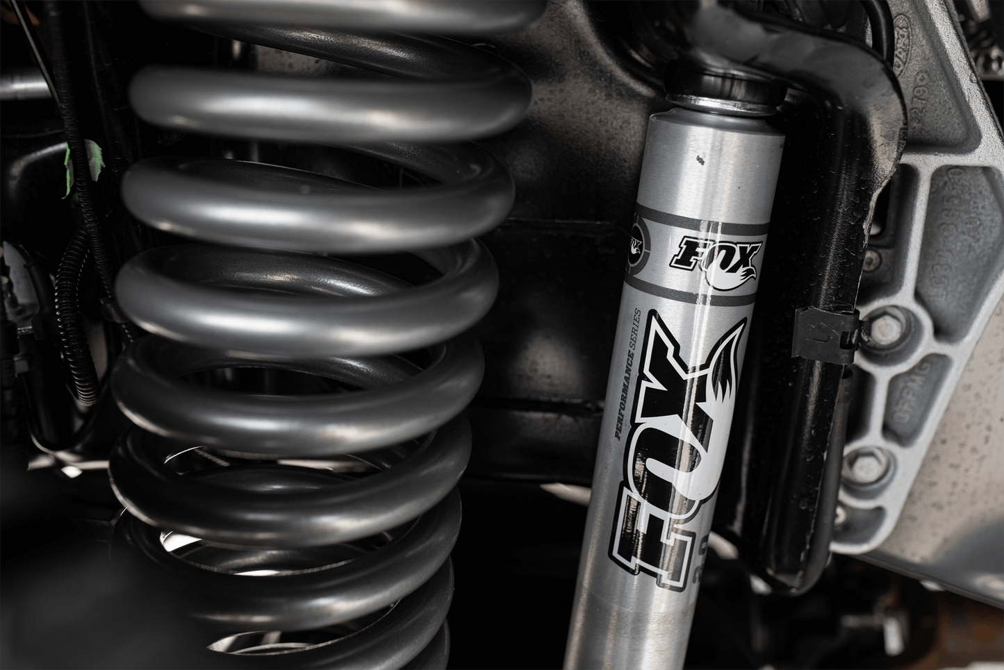
                  
                    Close-up view of a FOX suspension shock absorber and coil spring in a 2022 ROUSH F-150's advanced suspension system.
                  
                