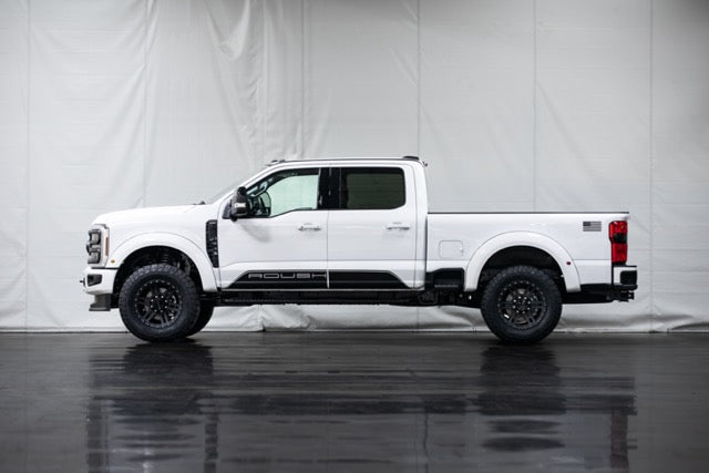 
                  
                    Side view of a white pickup truck with black accents and large tires, featuring a performance suspension, parked indoors against a plain backdrop.
                  
                