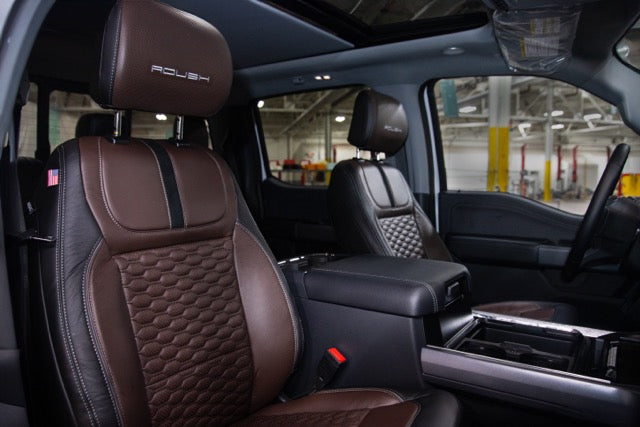 
                  
                    The interior of the Roush Super Duty showcases brown leather seats with quilted patterns, a center console, and a visible American flag detail on the seat, perfectly complementing its turbodiesel V8 engine.
                  
                